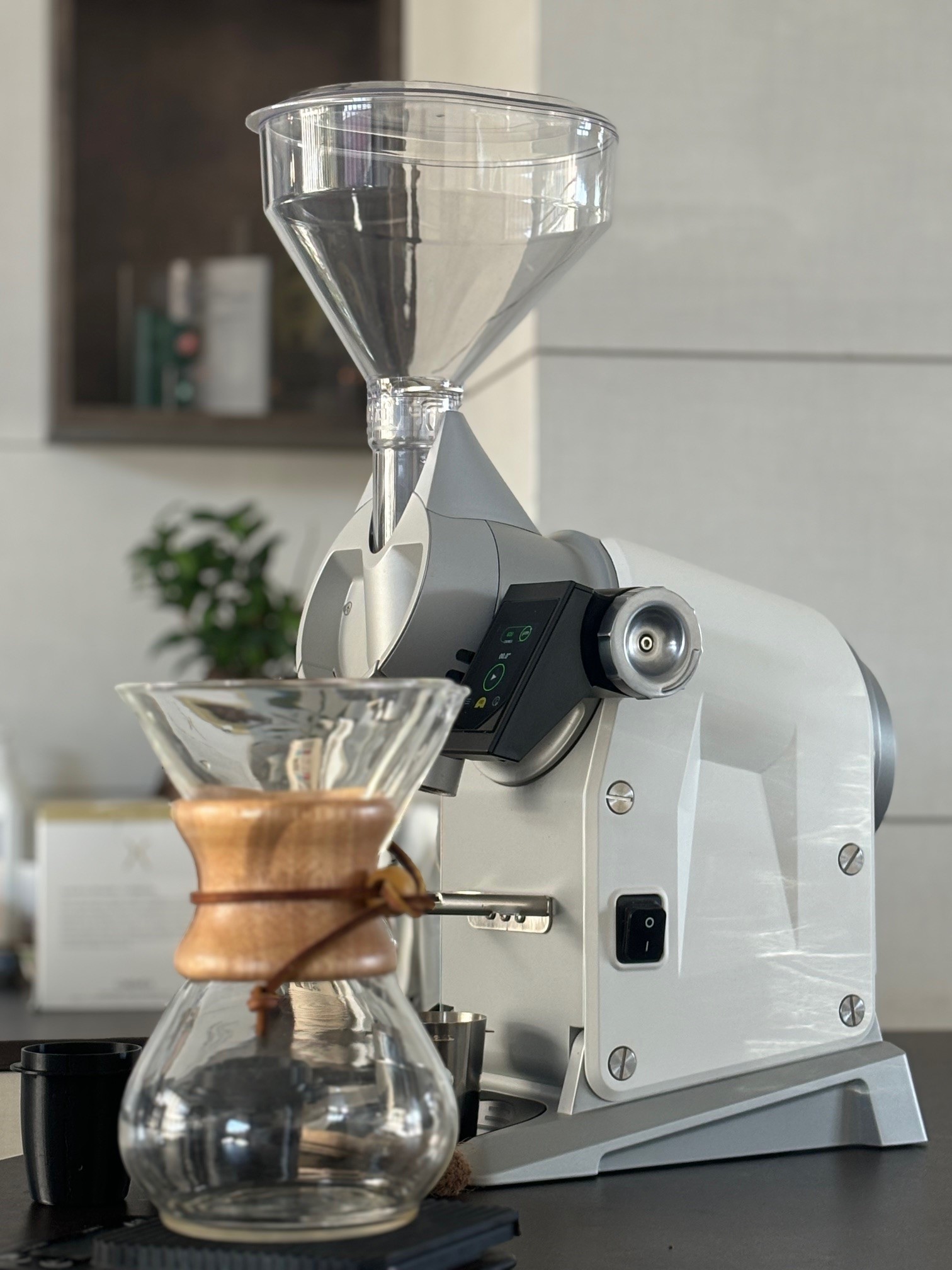 White Casadio grinder beside a glass brewer on a café counter.