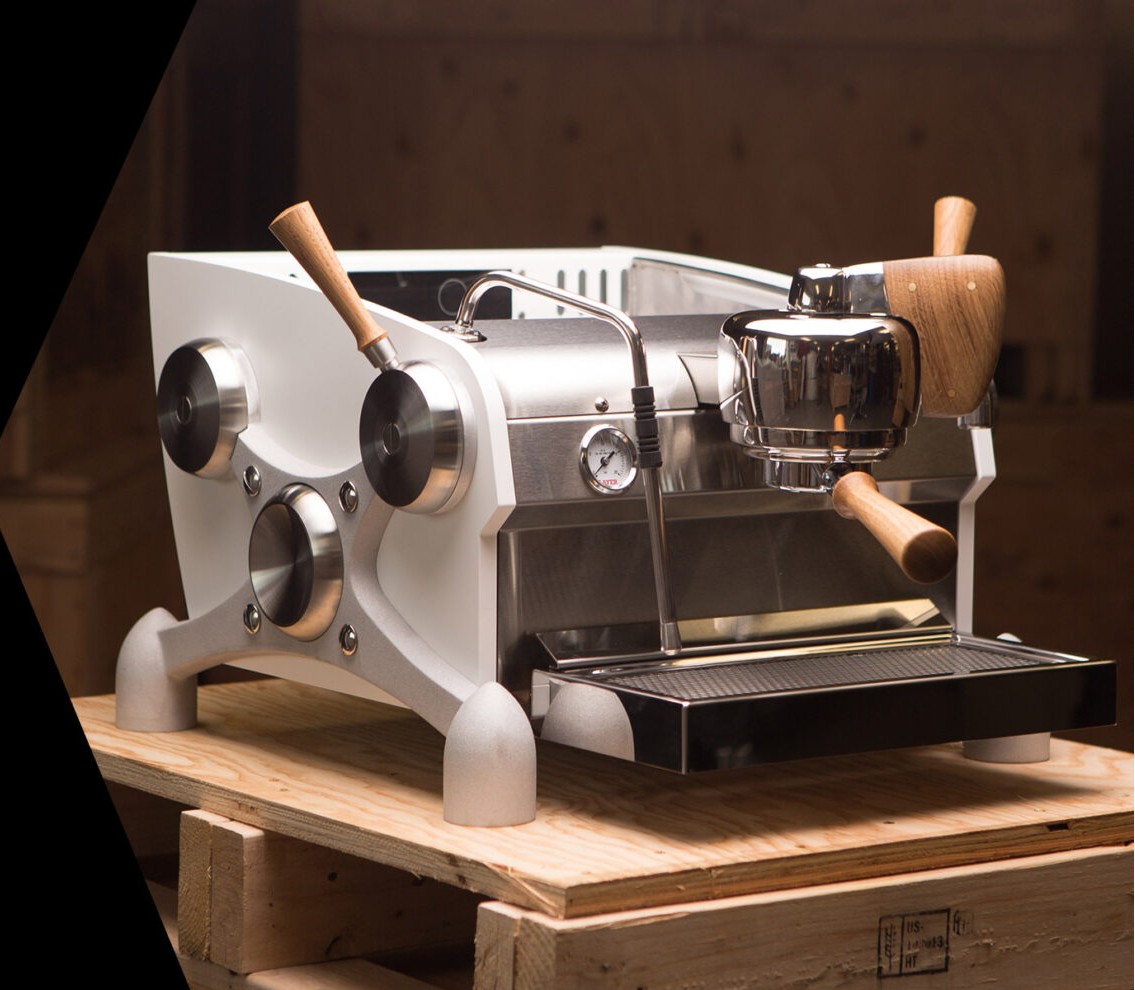 Single-group Slayer espresso machine with walnut handles, on a timber crate.
